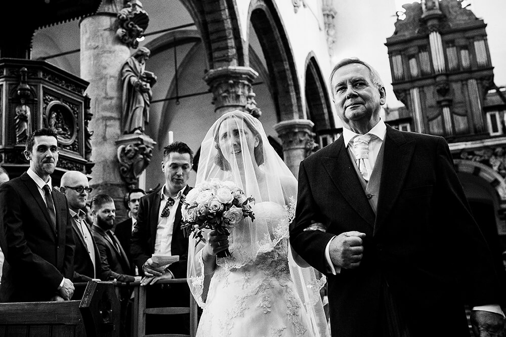 naar het altaar, bruid met papa, zwart wit fotografie, huwelijk Sint-Laureins, trouwfotograaf