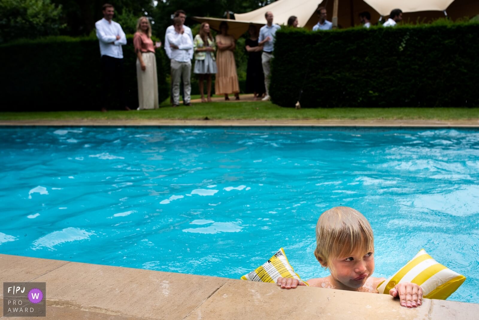 day in the life foto van een kleine jongen in een zwembad met grote zwembandjes aan