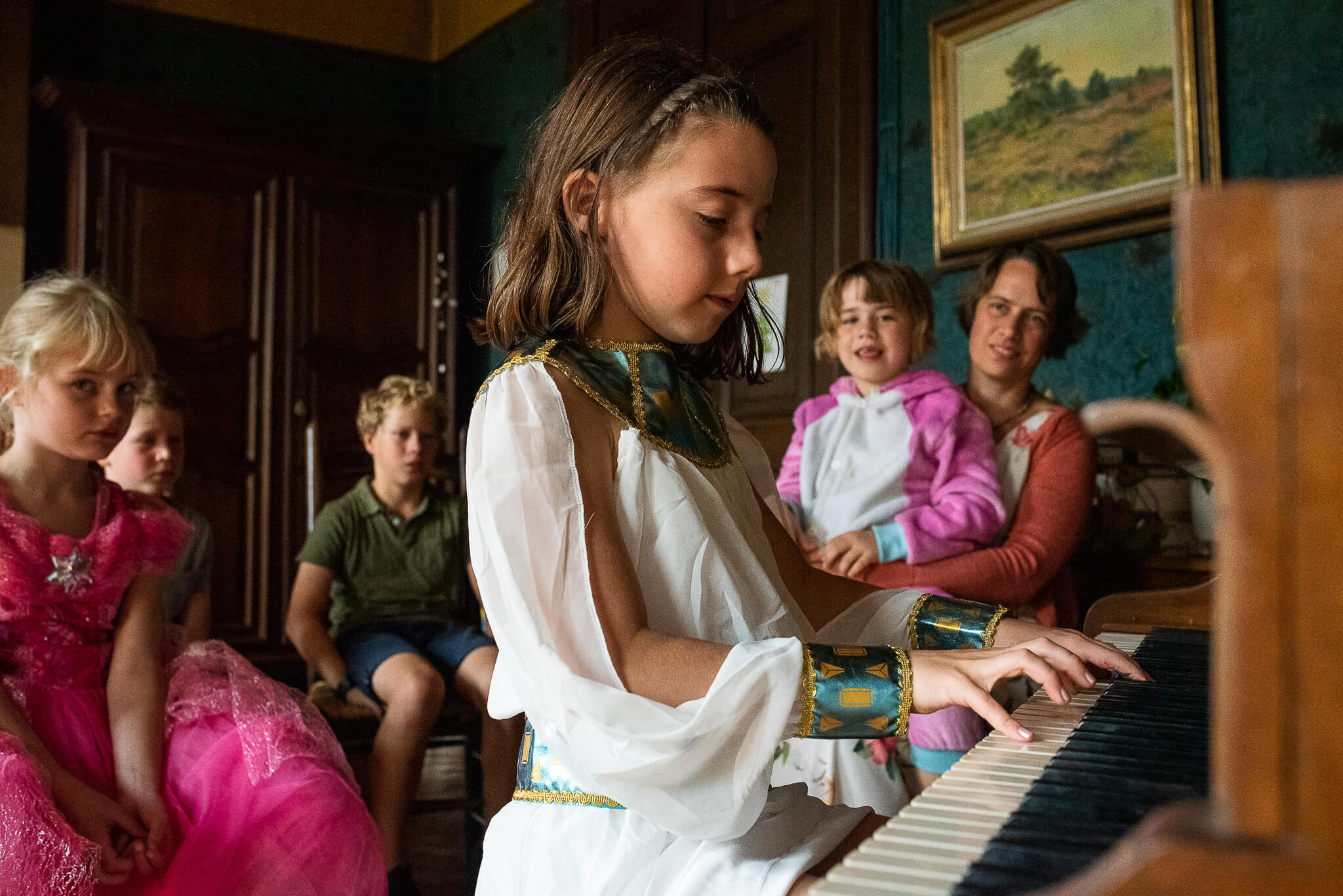 meisje speelt piano voor familie tijdens fotoreportage