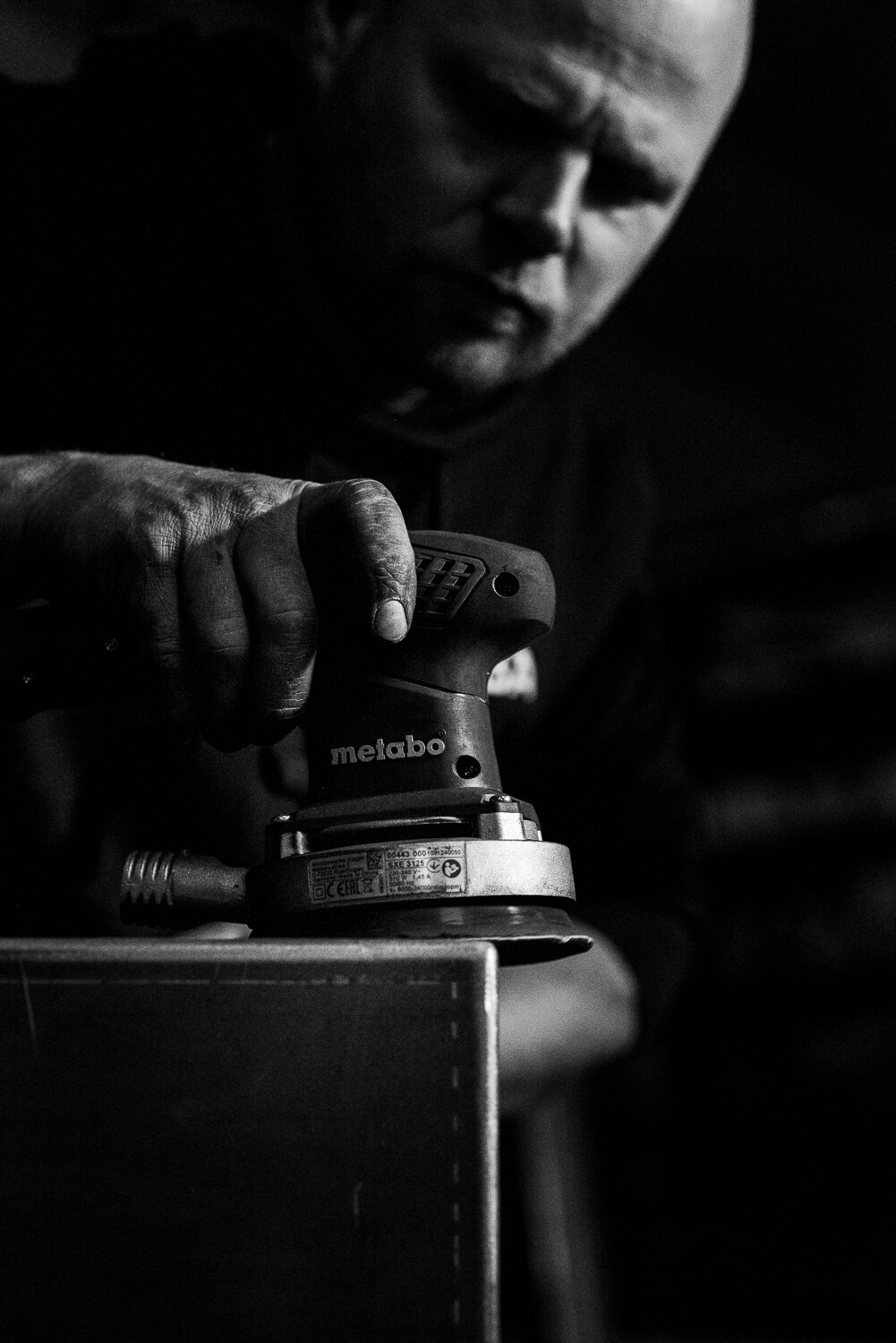 metaalbewerker aan het schuren door bedrijfsfotograaf